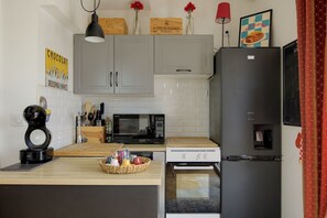 Eine Küche mit grauen Schränken, einer Mikrowelle, einem Kühlschrank und einer Kaffeemaschine.