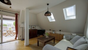 Ett modernt vardagsrum med en soffa, ett soffbord, en tv och ett fönster.