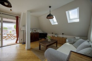 Ein modernes Wohnzimmer mit einer Couch, einem Couchtisch, einem Fernseher und einem Fenster.