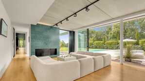 Ein modernes Wohnzimmer mit einer großen Eckcouch, einem Flachbildfernseher und Blick auf einen Swimmingpool.