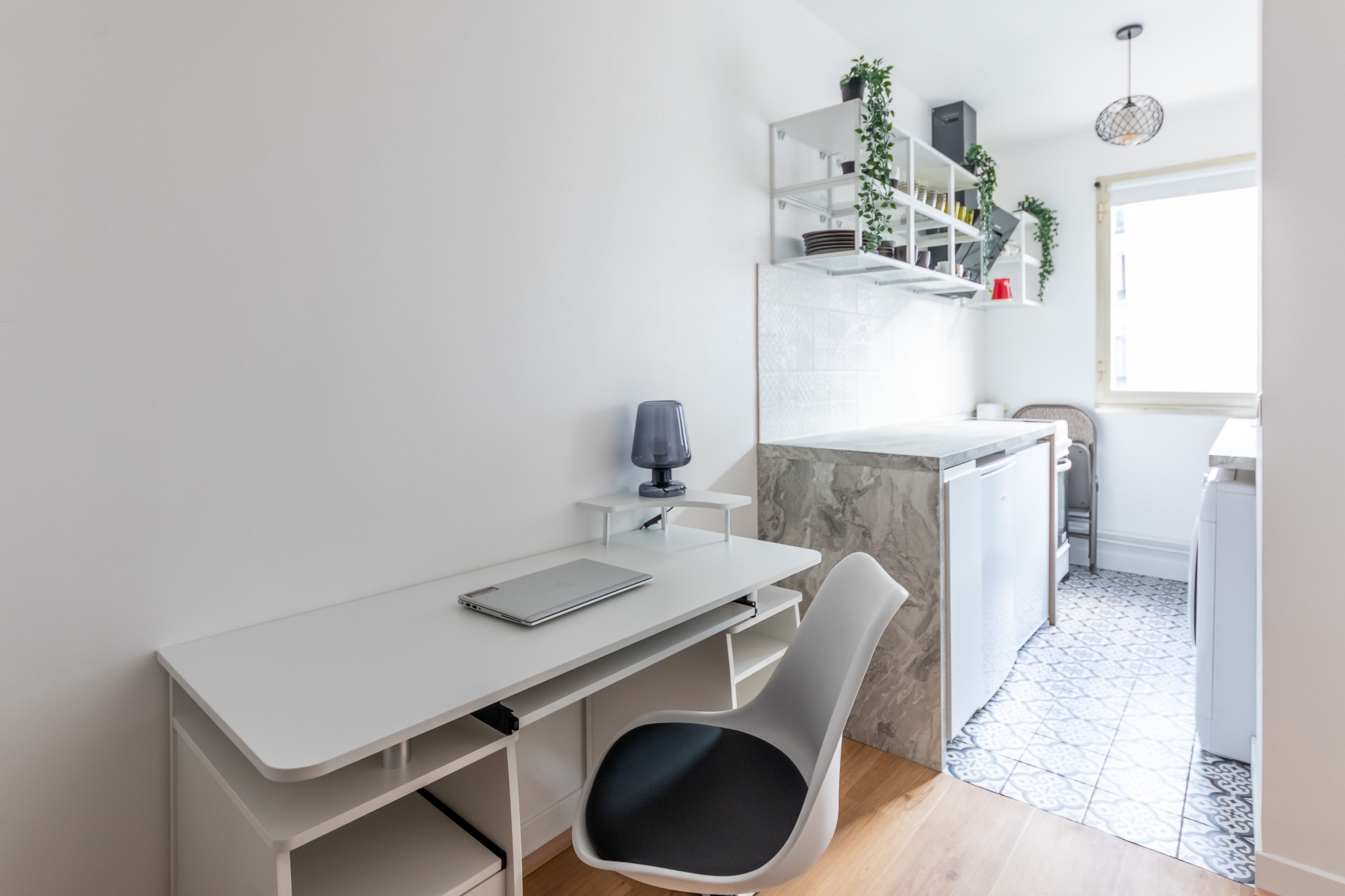 Une cuisine moderne avec des meubles blancs, un plan de travail en marbre et une cuisinière intégrée.