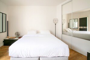 A modern bedroom with a large bed, bedside tables, a floor lamp, and a mirror. - Mouffetard Studio - À moins d'1 km du métro (Paris)