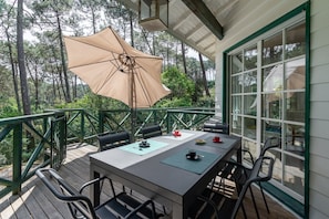 Een terras met een tafel, stoelen en een grote parasol.
