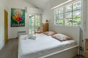 Een slaapkamer met een bed, een raam, een radiator, een lamp en een poster aan de muur.