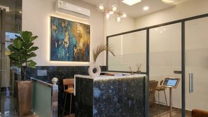 A modern reception area with a marble counter, a ceiling fan, and a large abstract painting.
