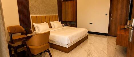 A modern hotel room with a bed, a desk, a chair, a ceiling fan, and an air conditioning unit.
