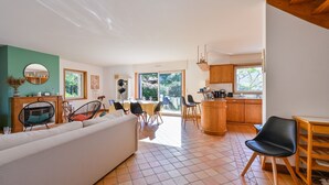 A modern living room with a sofa, dining area, kitchen, and large windows. - Penty du Trehiat - À moins d'1 km de la plage (Sarzeau)