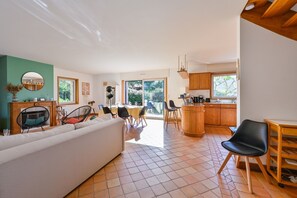 Ein modernes Wohnzimmer mit Sofa, Essbereich, Küche und großen Fenstern.
