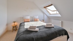 A bedroom with a skylight, a bed with pillows, a bedside table with a lamp, and a radiator. - Penty du Trehiat - À moins d'1 km de la plage (Sarzeau)