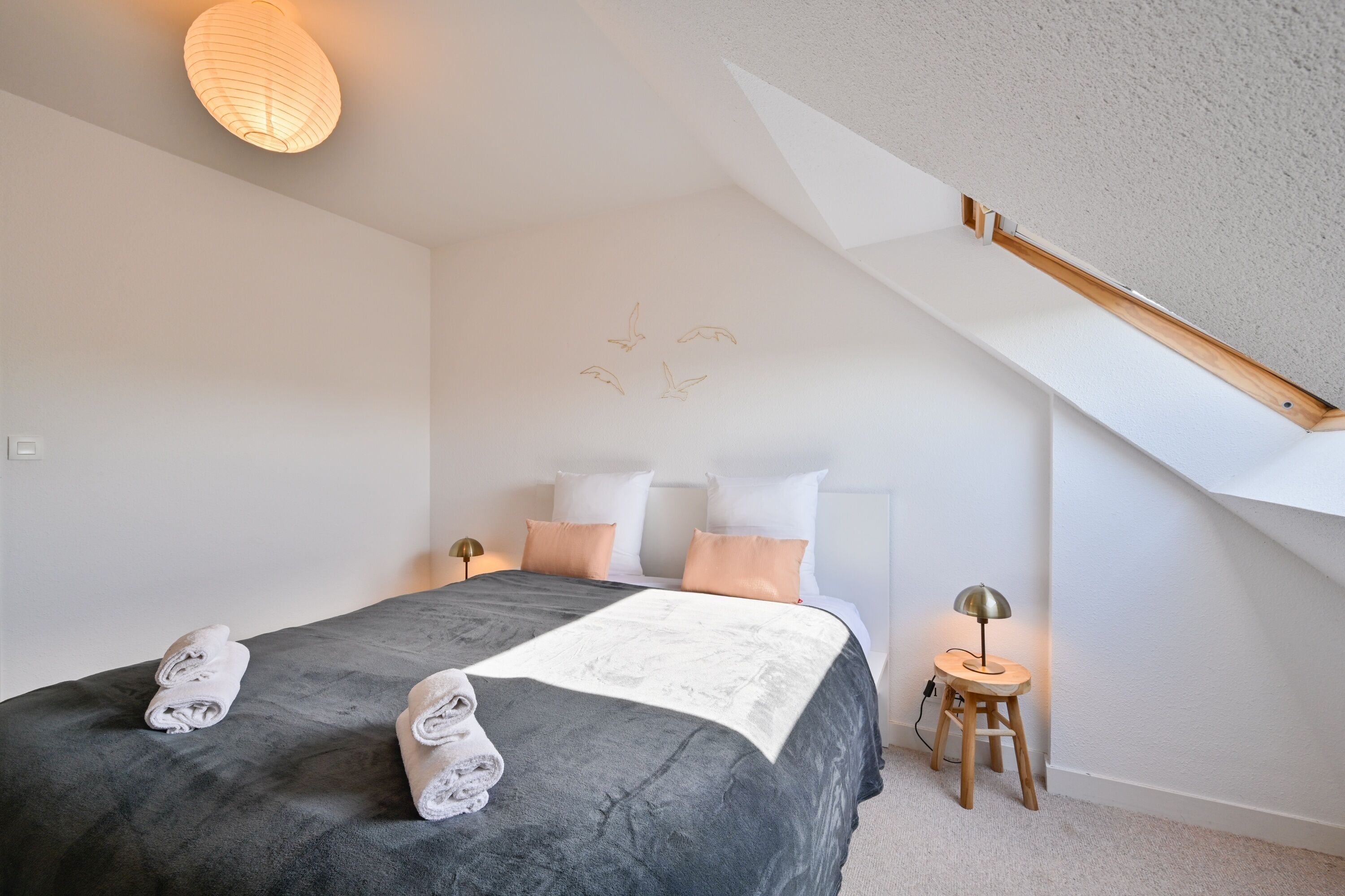 A bedroom with a bed, a nightstand, a lamp, and a ceiling light.