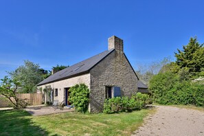 Una casa de piedra con chimenea, camino de grava y jardín cubierto de césped.