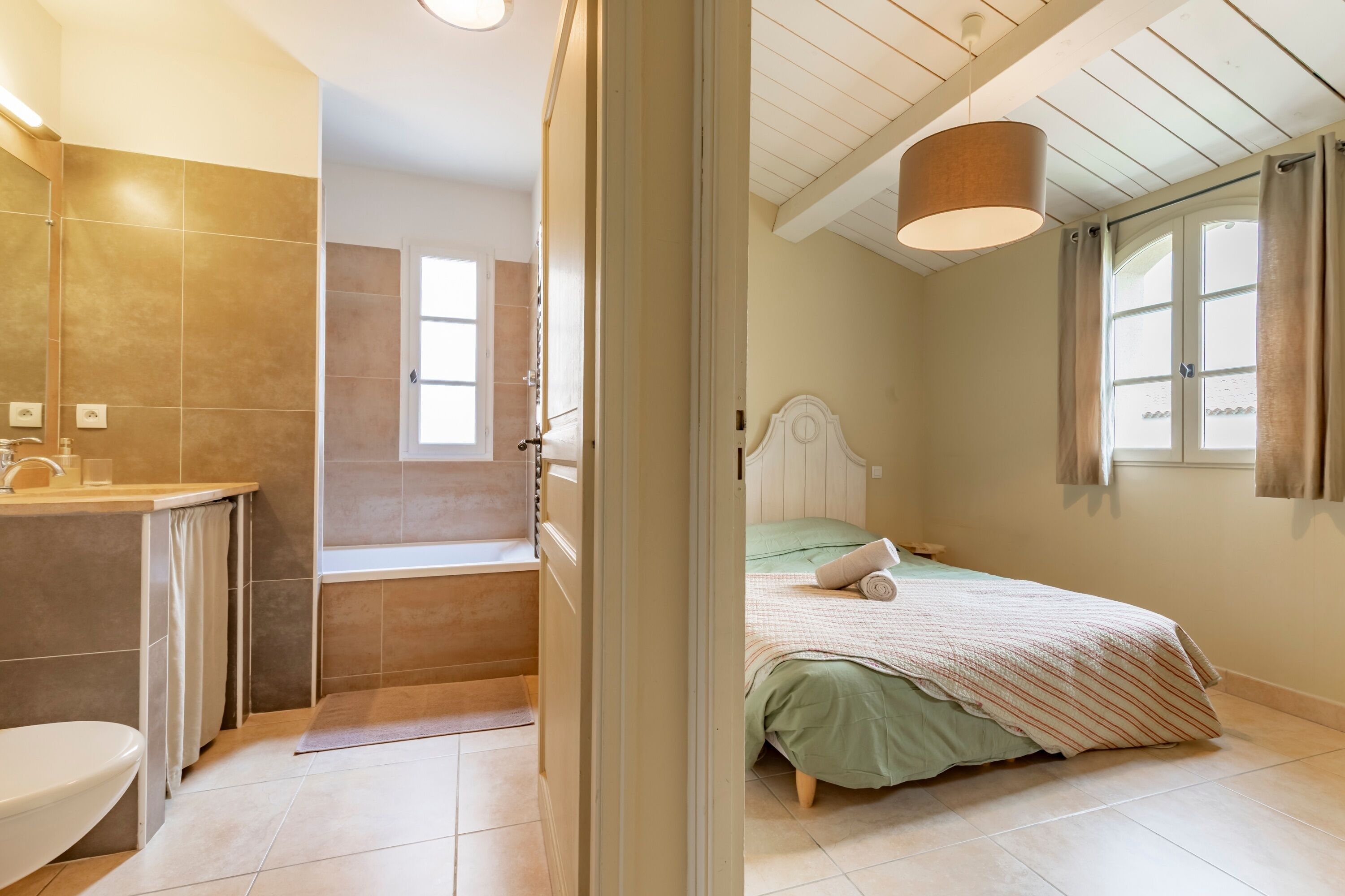 Un dormitorio con cama, ventana y baño con bañera.