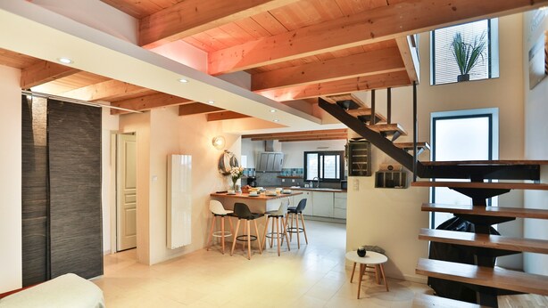 A spacious kitchen with a central island, a dining area with chairs, and a staircase leading to an upper level. - L'Airial - Charmante maison aux Sables (Les Sables d'Olonne)
