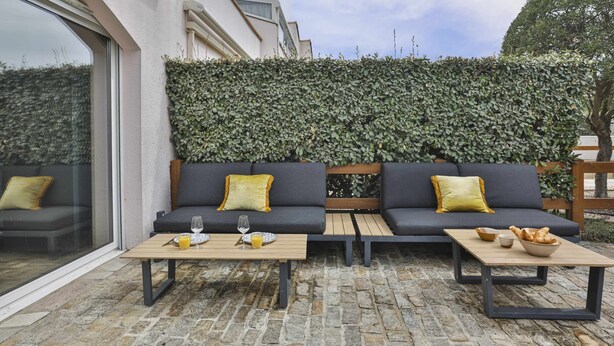 An outdoor seating area with two sofas, two tables, and a hedge wall. - L'Océanide - dans une belle résidence avec piscine (Bretignolles-sur-Mer)