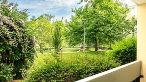A balcony with a view of a lush garden, a street lamp, and a clear sky. - L’Écrin Vert d’Angers - À 100 m du tramway (Angers)