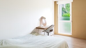 A bedroom with a bed, a desk with a chair, a window, and a view of greenery outside. - L’Écrin Vert d’Angers - À 100 m du tramway (Angers)