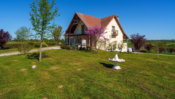 Une maison avec un toit en pente, une pelouse bien entretenue et une statue au premier plan.