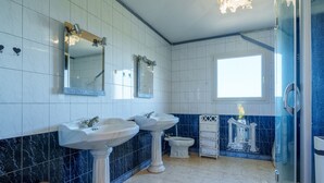 Une salle de bain avec deux lavabos, des toilettes et une douche.