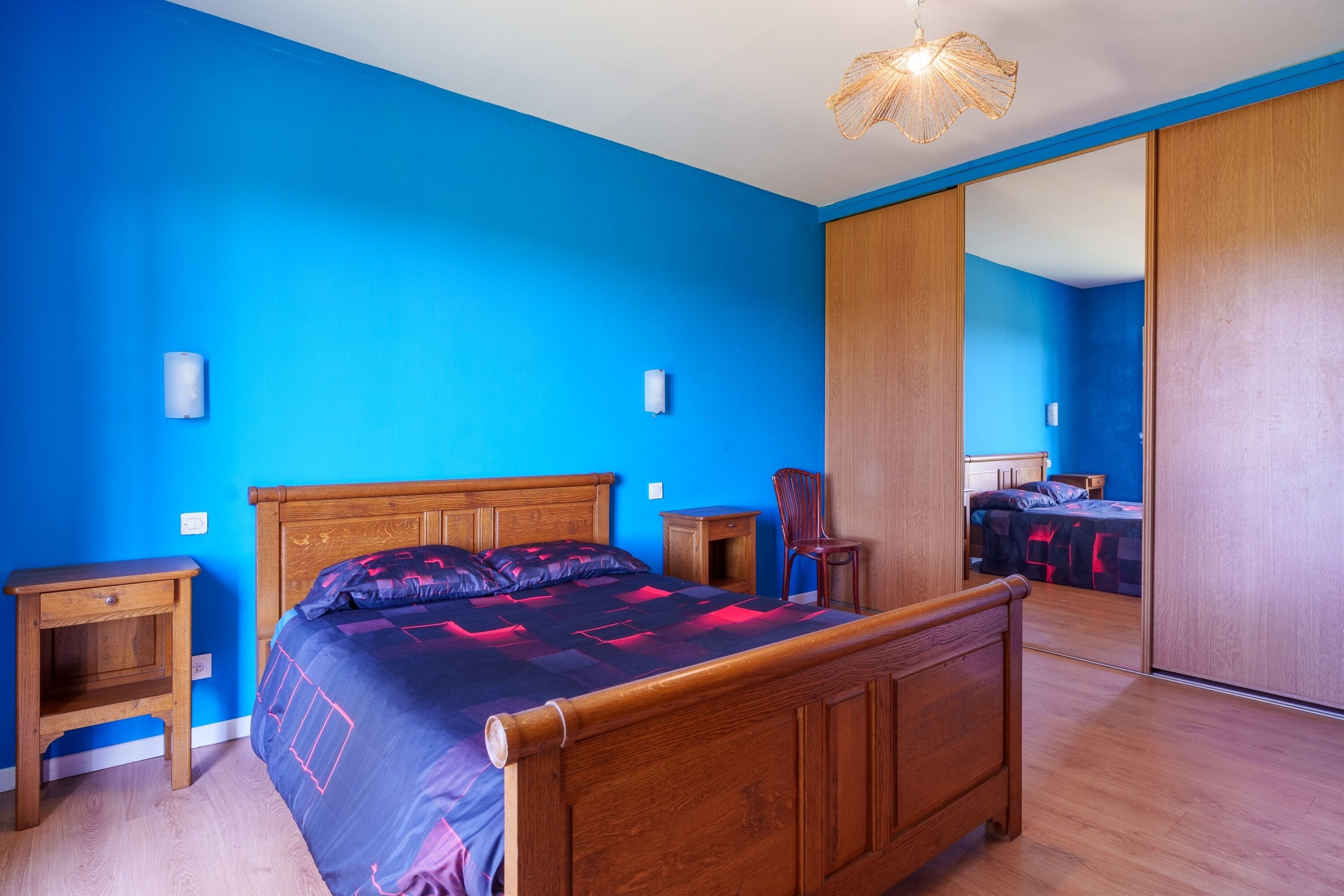 Une chambre à coucher avec un lit en bois, une table de chevet, une chaise et une armoire.
