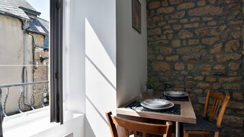 Un espace repas comprenant une table, des chaises et une vue par la fenêtre.