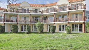 Ein mehrstöckiges Hotel mit Balkonen, einem gepflegten Rasen und blauem Himmel.