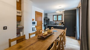 A modern kitchen with a wooden table, chairs, and a built-in oven.