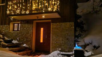 Een gebouw met een stenen gevel, een houten deur en een balkon met lichtjes.