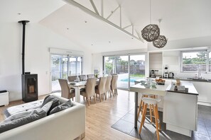 Eine moderne Küche mit Essbereich, Einbauherd und großem Fenster mit Blick auf einen Garten.