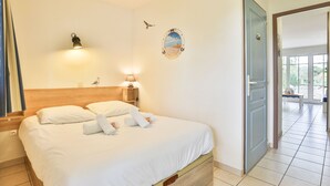 Ein Hotelzimmer mit einem Bett, einem Nachttisch, einer Wandlampe, einem Spiegel und einer Tür, die auf einen Balkon führt.