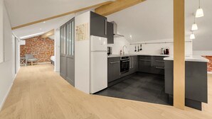 Una cocina moderna con techo de madera, un refrigerador, un horno y un lavamanos.