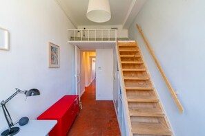 Eine Treppe mit Holzgeländer, einer roten Bank und einem Schreibtisch mit Lampe.