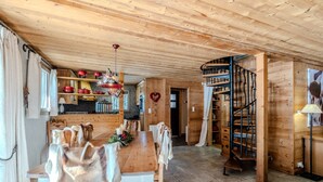 Ein Holzinterieur mit einem Esstisch, Stühlen, einer Treppe und einer herzförmigen Dekoration.