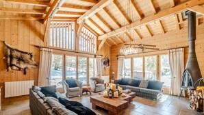 Ein gemütliches Blockhaus-Interieur mit großem Kamin, Holzwänden und einer Sofagarnitur.