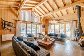 A cozy log cabin interior with a large fireplace, wooden walls, and a sofa set. - Chalet Le Lochet - Calme et chaleureux pour 8 (Sixt-Fer-à-Cheval)