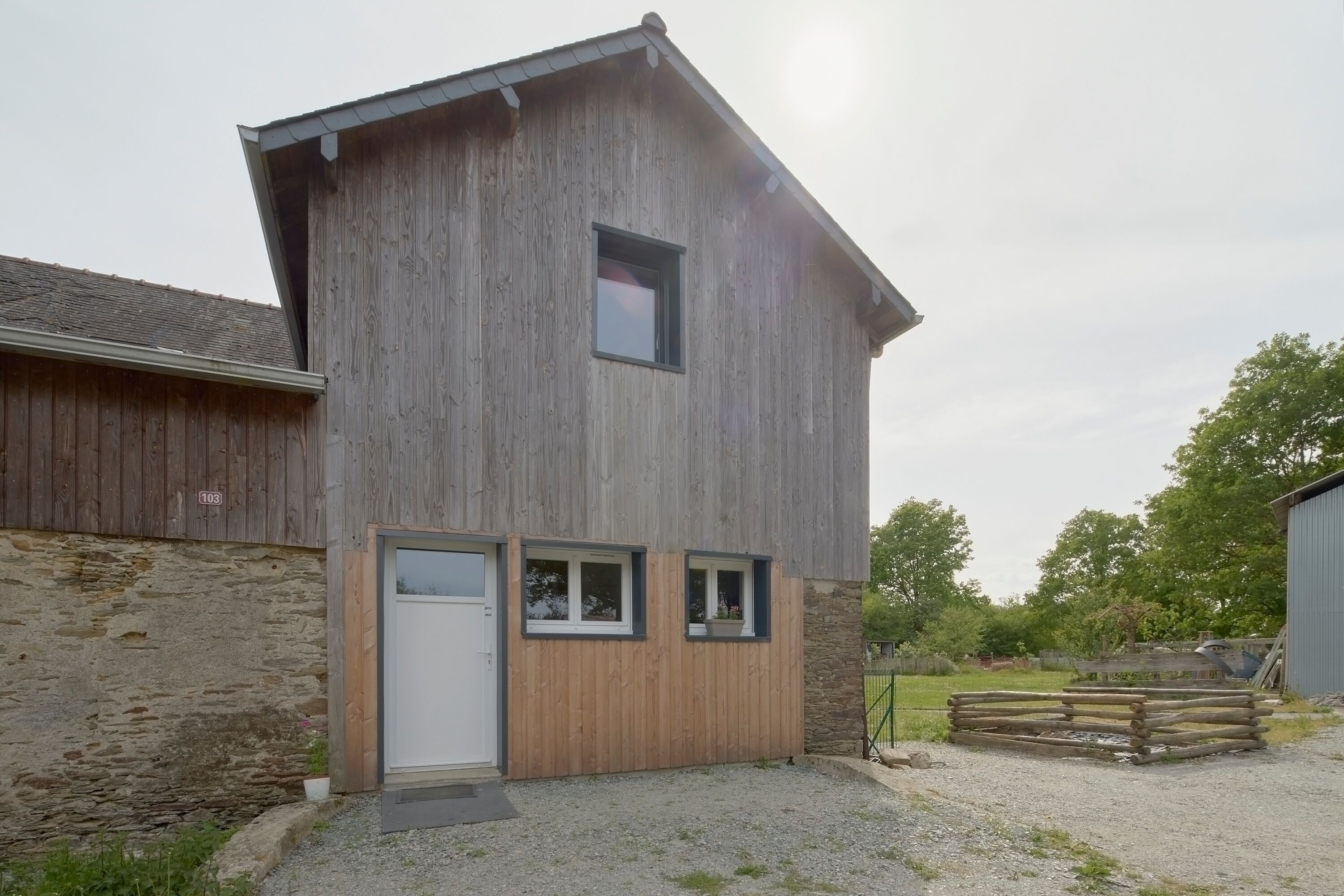 A wooden building with a door, two windows, and a small porch area.