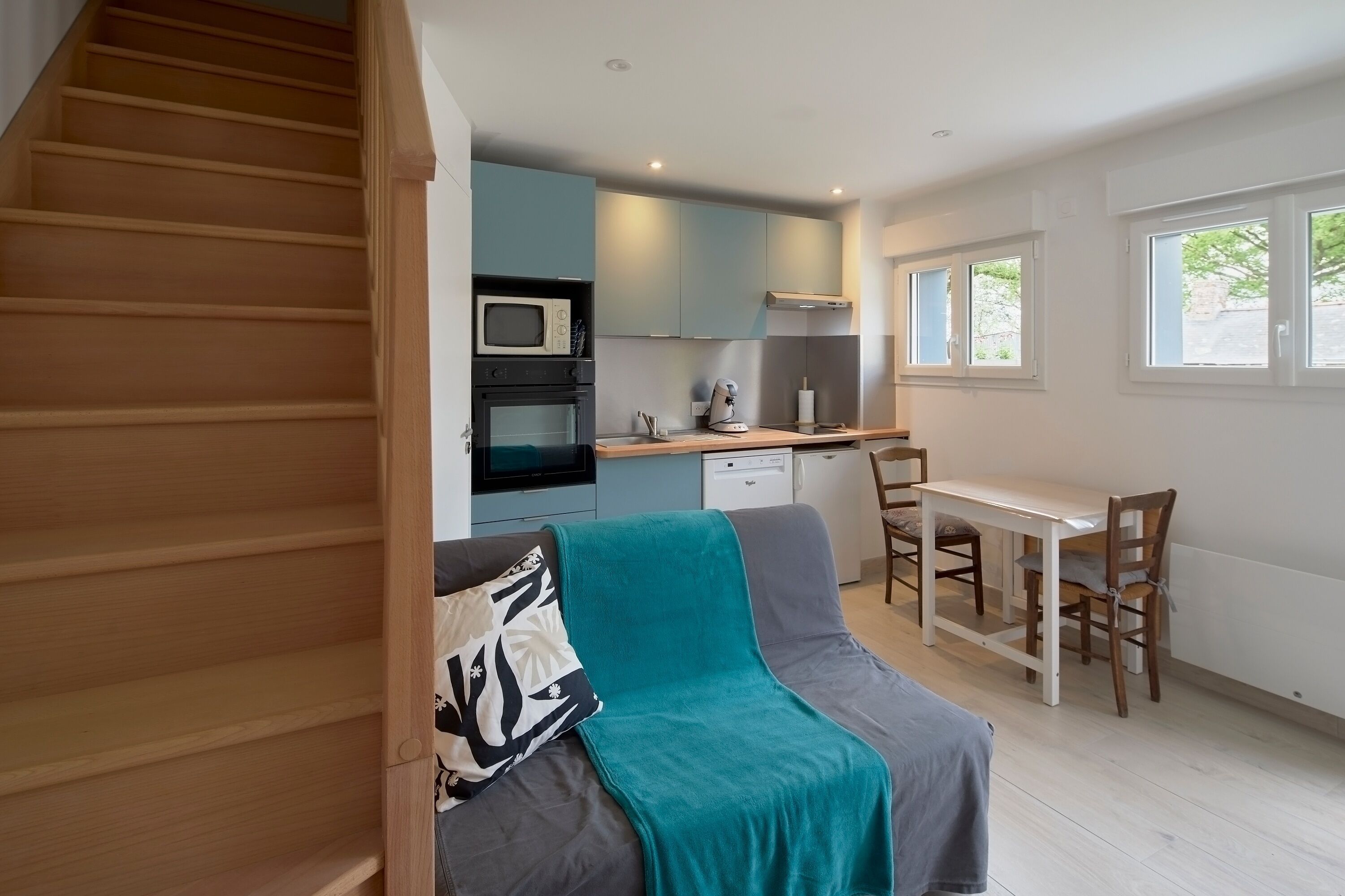 A compact living space with a kitchenette, a dining area, and a staircase.