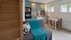A compact living space with a kitchenette, a dining area, and a staircase. - La Sittelle - Appt pour 4 à 25 km de Nantes (Héric)