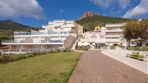 Een modern hotel met meerdere balkons, een centrale binnenplaats en een berg op de achtergrond.