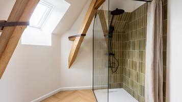 Eine moderne Dusche mit Glastüren, Holzboden und Dachfenster.