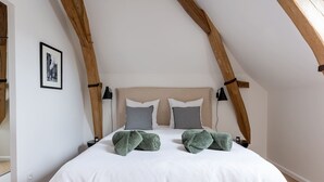 A bedroom with a high ceiling, exposed wooden beams, a bed with white linens, two pillows, and a framed picture on the wall. - Louisa - Entre Nature et Loisirs (Saint-Calais)