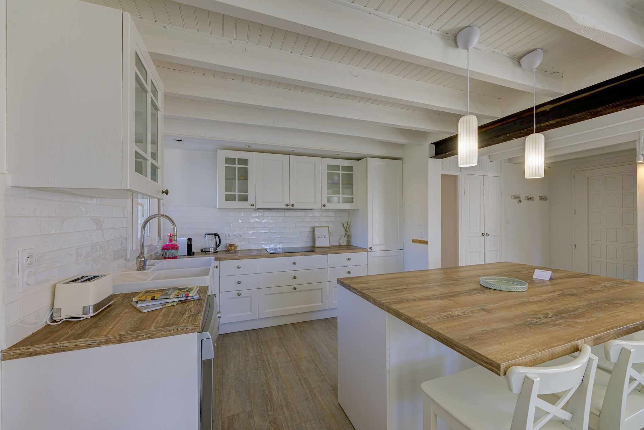 A kitchen with white cabinets, a wooden countertop, and a wooden dining table with chairs.
