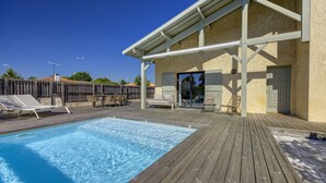 Eine Holzterrasse mit Pool, Sitzgelegenheiten im Freien und einer überdachten Veranda.