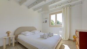Ein Schlafzimmer mit Bett, Nachttisch, Lampe und einem Fenster mit Vorhängen.