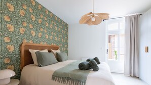Una camera da letto con un letto, un comodino, una lampada a sospensione e vista sull'esterno.