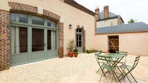 Un edificio con facciata in mattoni, ampie finestre e un patio con tavolo e sedie.