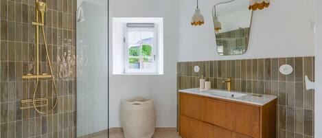A bathroom with a shower, vanity, and a window with a view.