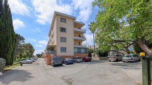 A multi-story building with a parking lot in front, a sign reading 'Le Saint Louis,' and several parked cars. - L'Ecrin d'Hyères - Appt à 10 min de la plage (Hyères)