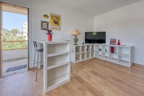Ein modernes Wohnzimmer mit Fernseher, einer Couch, einem Couchtisch und einer Balkontür.