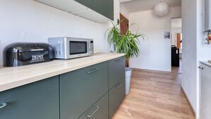 A kitchenette with a microwave, toaster, and a potted plant. - L'Ecrin d'Hyères - Appt à 10 min de la plage (Hyères)