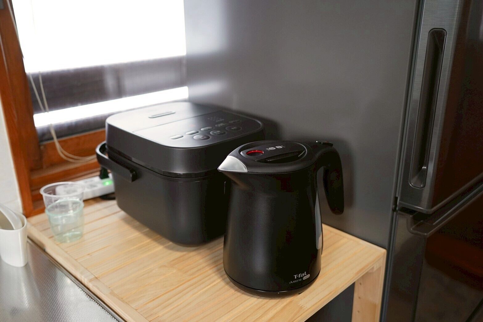 A kitchen with a coffee maker, a food processor, and a refrigerator.